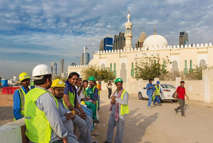 Travailleurs de la construction faisant une pause à côté d'une mosquée dans le centre moderne de Dubaï.