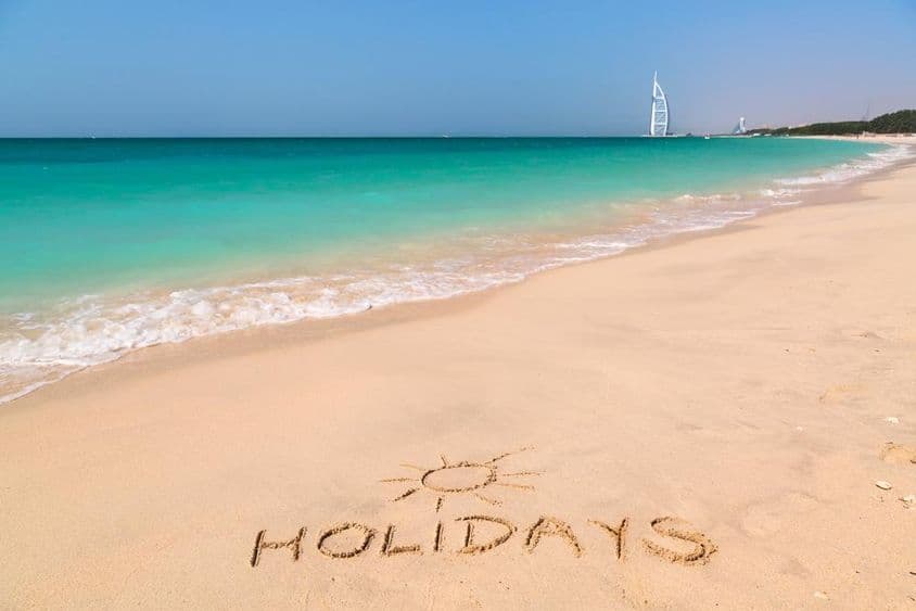 Panneau de vacances sur une plage de sable.