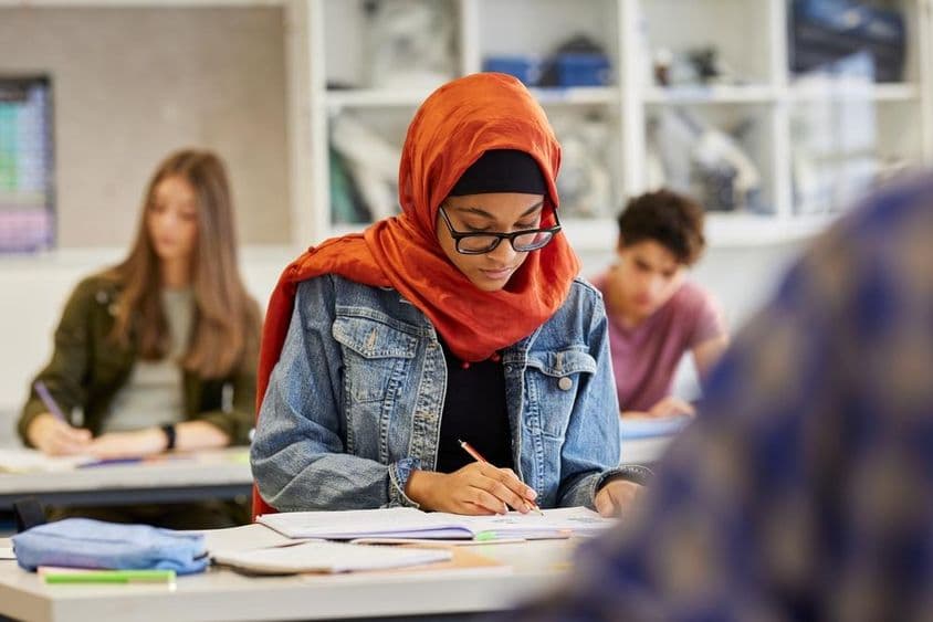 Jeune étudiante portant un hijab étudiant en prenant des notes.