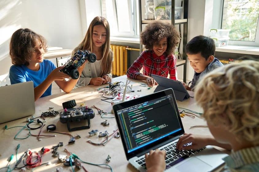 Des écoliers construisant des voitures robotiques en utilisant des ordinateurs et la programmation.