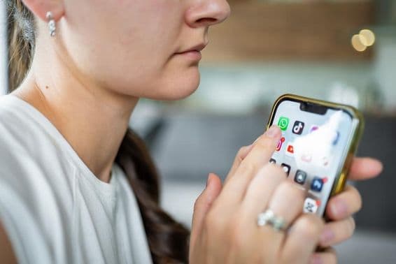 Femme tenant un iPhone avec l'application de chat WhatsApp à l'écran.