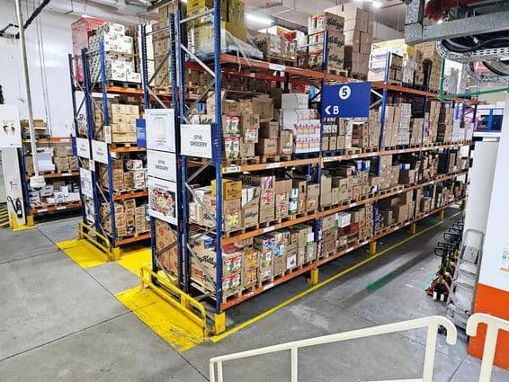 Entrepôt avec systèmes d'étagères, catégories de produits étiquetées et marquages de sécurité aidant le bon fonctionnement.