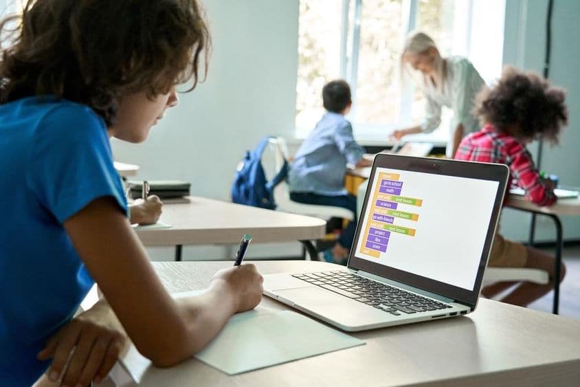 Élève de lycée utilisant un ordinateur portable pour saisir des données de codage.