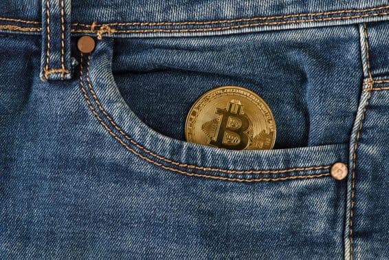 Une pièce de bitcoin en or repose dans une poche de jeans.