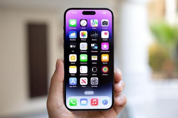 Homme tenant un iPhone 15 Pro Max avec iOS 17 à l'écran.