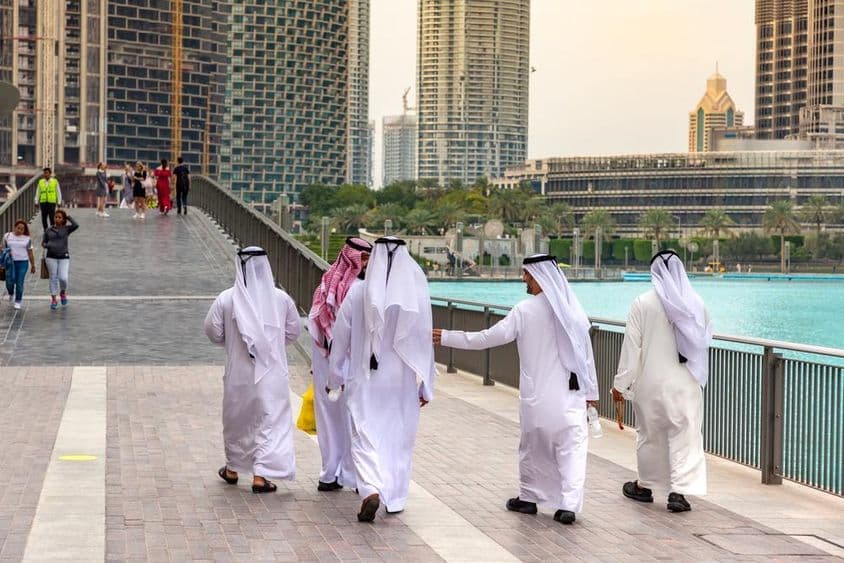 Hommes arabes en tenue traditionnelle blanche marchant dans le centre-ville de Dubaï.