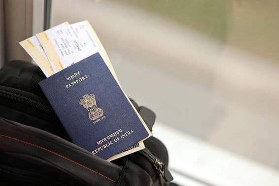 Passeport indien bleu avec billets d'avion sur un sac à dos de voyage.