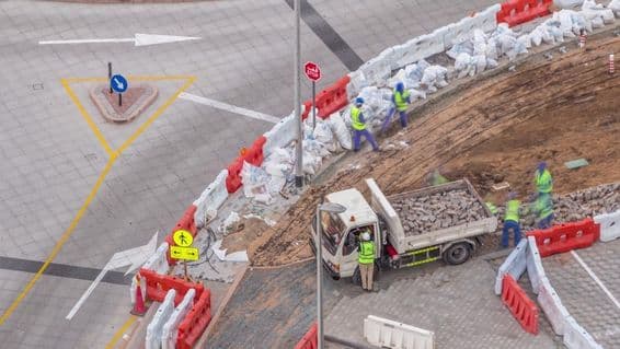 Processus de réparation de trottoir avec de nombreux ouvriers de construction et équipements cassant le trottoir et le béton.