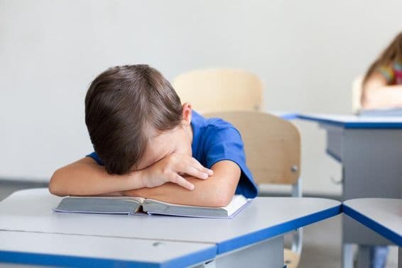 Enfant scolaire dormant pendant un cours ennuyeux.