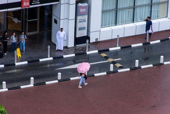 Une fille avec un parapluie marchant sous la pluie dans la ville de Dubaï.