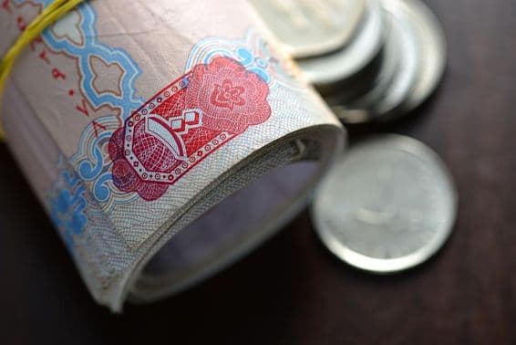 Des dirhams émiratis roulés accompagnés de quelques pièces.