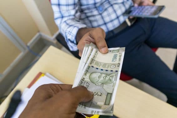 Une personne remettant un billet de banque indien de 500 roupies à une autre personne.
