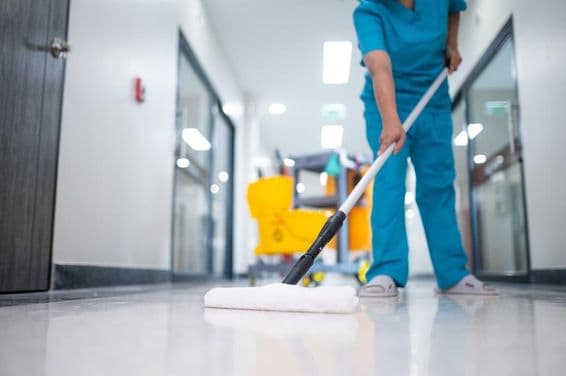 Nettoyeur passant la serpillière sur le sol du hall.