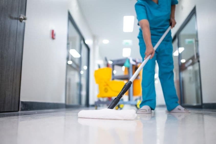 Nettoyeur passant la serpillière sur le sol du hall.