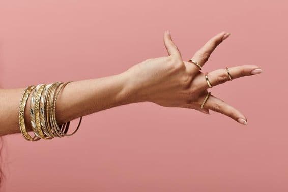 Femme indienne posant élégamment avec des bracelets en or à son poignet.