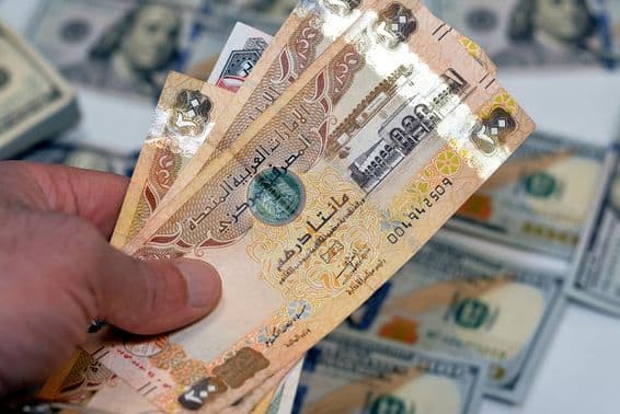 Un homme tenant une liasse de billets de 200 dirhams des Émirats arabes unis.