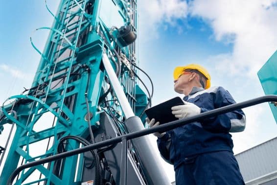 Opérateur industriel utilisant une tablette numérique pour contrôler une plateforme de forage.