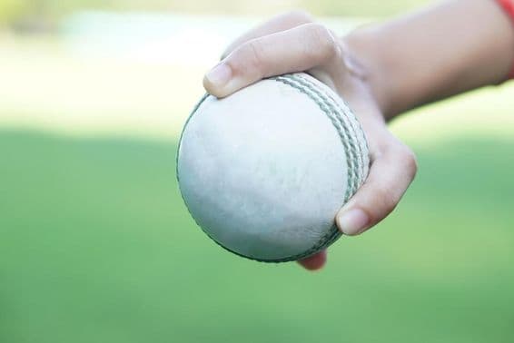Un joueur de cricket tenant une balle de cricket en cuir blanc.