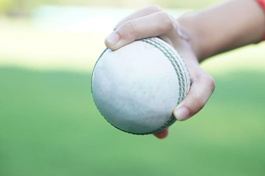 Un joueur de cricket tenant une balle de cricket en cuir blanc.