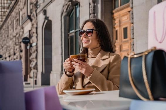 Une fille portant des lunettes de soleil buvant du café.