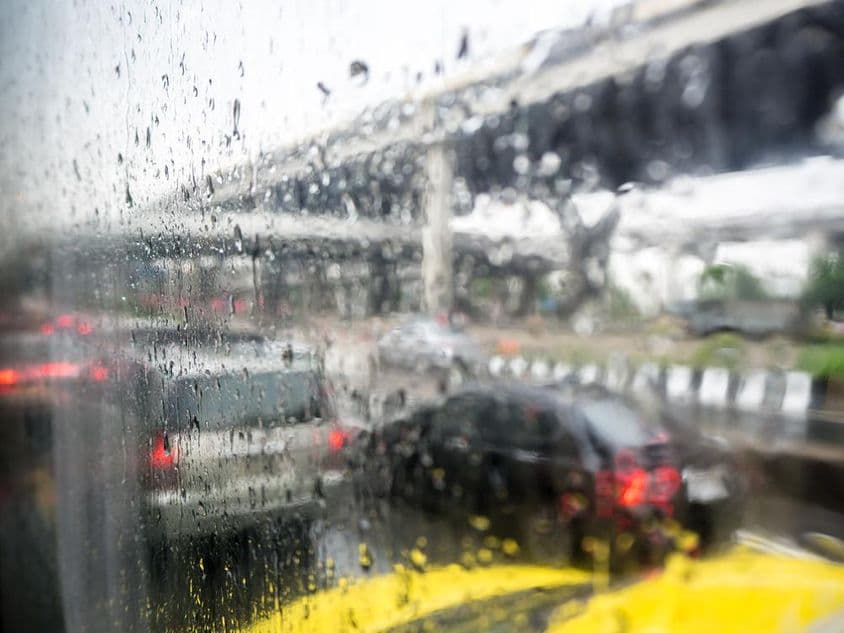 Trafic lors d'un jour de pluie avec des gouttes de pluie sur la vitre de la voiture.