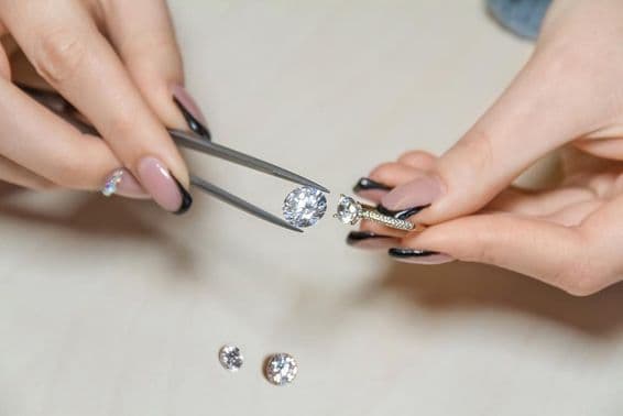 Mains de femme joaillière tenant une pierre précieuse.