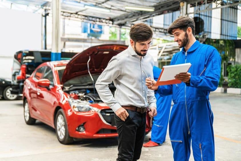 Mécanicien montrant la liste de vérification de l'inspection automobile à un client.