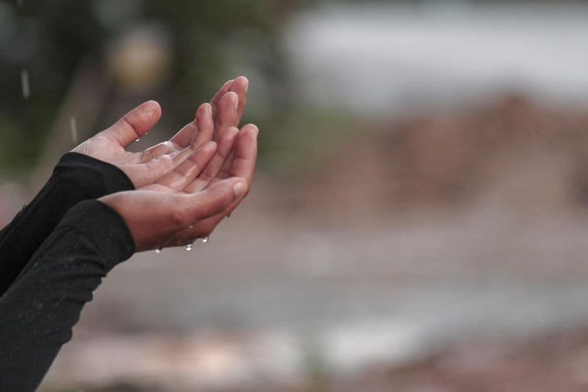 Une femme priant les mains levées pour la pluie.