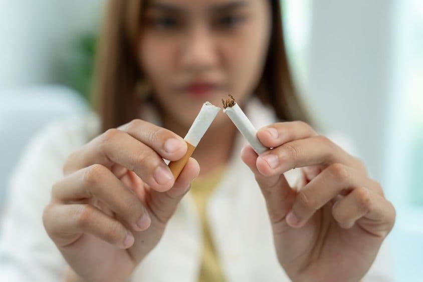 Pas de tabac, une femme casse une cigarette en deux.