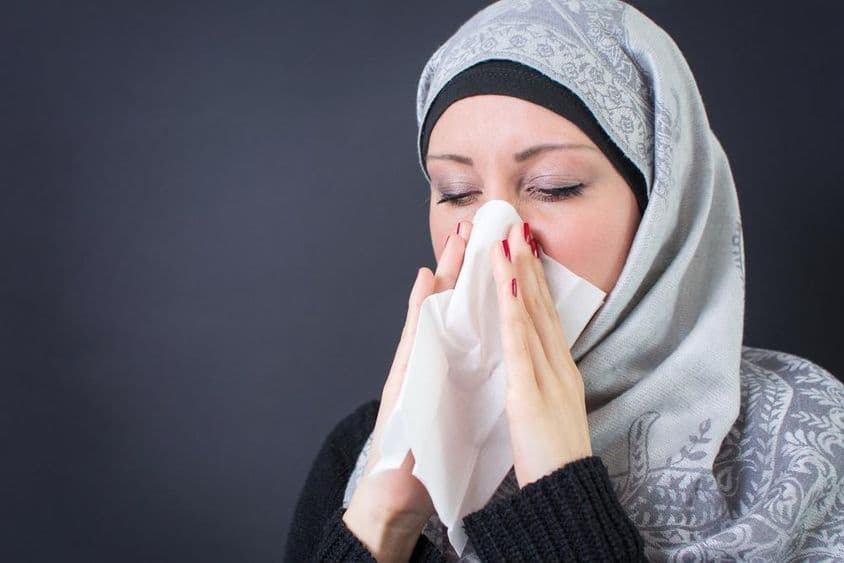 Une belle femme musulmane avec un rhume et le nez qui coule.