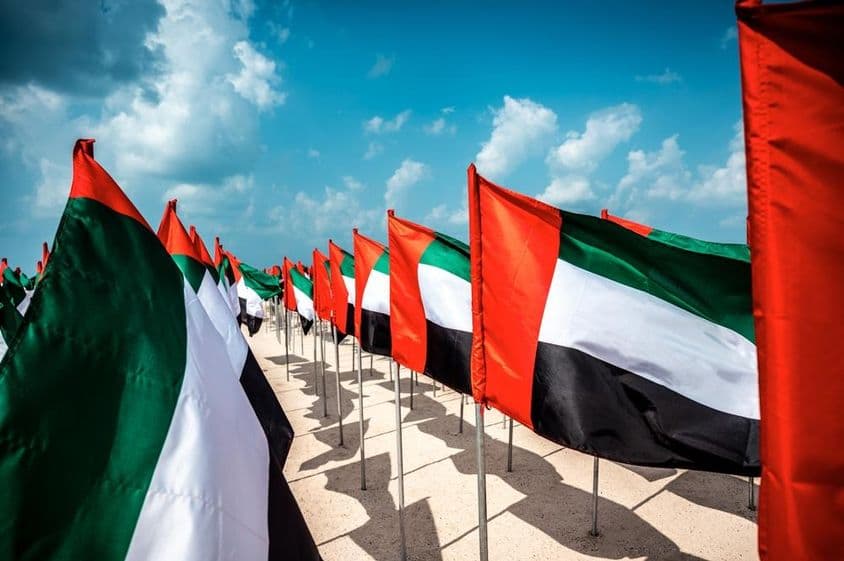 Drapeaux des Émirats Arabes Unis flottant au vent sur une plage populaire de Dubaï.