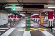 Un garage de stationnement spacieux, vide et moderne à Dubaï avec un éclairage lumineux et une signalisation claire.