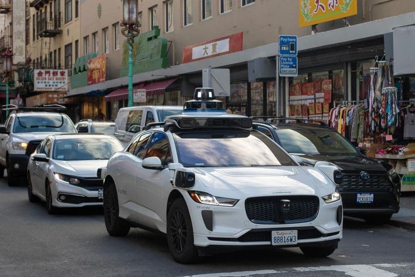 Robotaxi Waymo naviguant dans les rues étroites et animées de Chinatown à San Francisco.