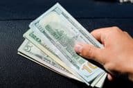 Une liasse de dollars dans la main d'un homme.