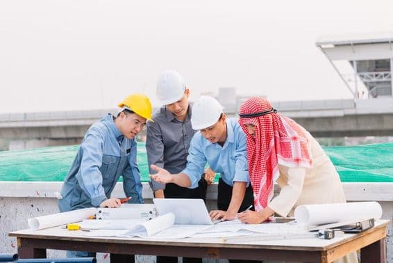 Homme d'affaires arabe, ingénieur et ouvrier discutant de plans de construction en utilisant un ordinateur portable.