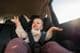 Bébé heureux applaudissant dans un siège auto pendant un voyage en famille.
