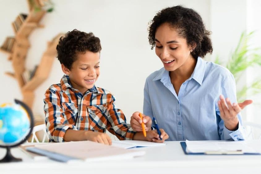 Jeune enseignante expliquant une leçon à un jeune garçon.