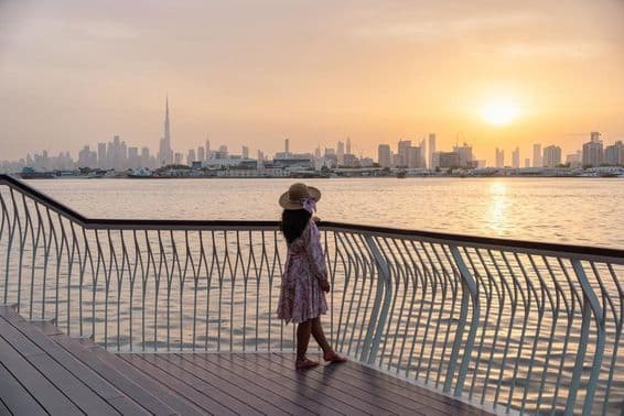 Jeune femme regardant le skyline de Dubaï au coucher du soleil.