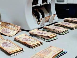 Machine à compter l'argent avec des liasses de billets de banque en dirhams émiratis disposées sur un bureau.