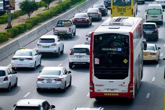Voie de bus à impériale et trafic diurne dans les rues de Dubaï.