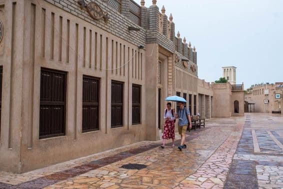 Un couple de touristes marchant sous un parapluie dans les rues de Dubaï.