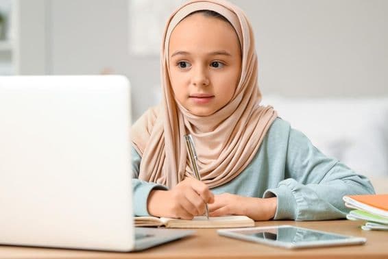 Petite fille musulmane en hijab faisant ses devoirs à la maison.
