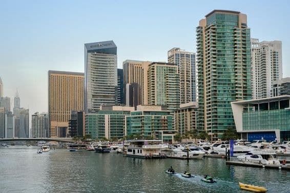 Vue nocturne du canal, port avec bateaux, promenade de Dubaï, et gratte-ciel.