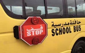 Un bus scolaire vide avec un panneau d'avertissement STOP rouge garé sur le côté.