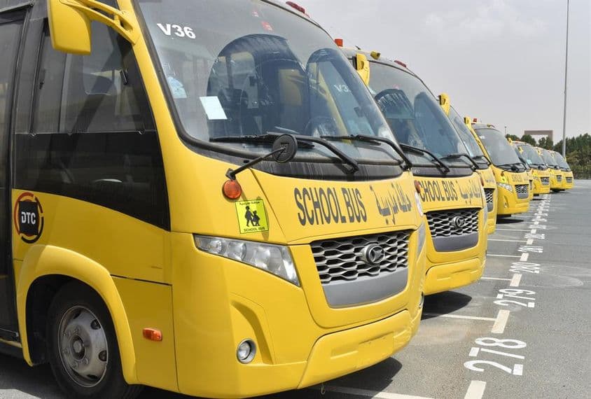 Plusieurs bus scolaires jaunes alignés dans un parking à Dubaï.