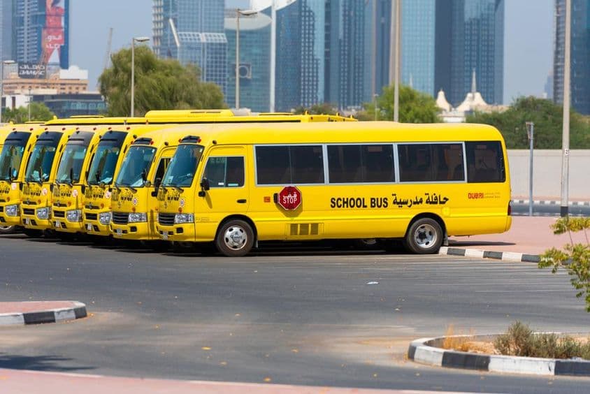 Alignement de bus scolaires jaunes de Dubaï garés à l'extérieur.