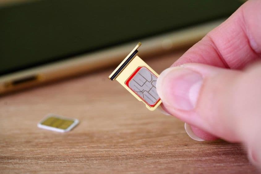 Personne insérant une carte SIM à l'arrière d'un téléphone mobile.