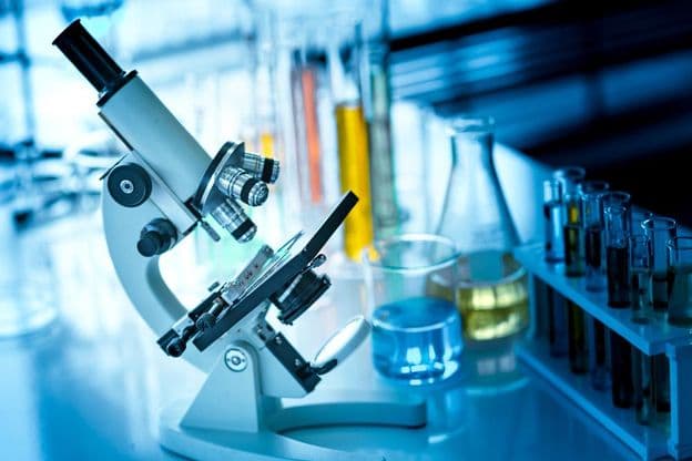 Microscope sur une table avec tubes chimiques et verrerie.