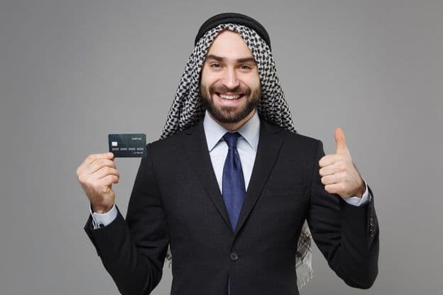 Homme d'affaires musulman arabe souriant avec une carte de crédit.