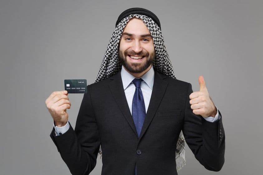 Homme d'affaires musulman arabe souriant avec une carte de crédit.